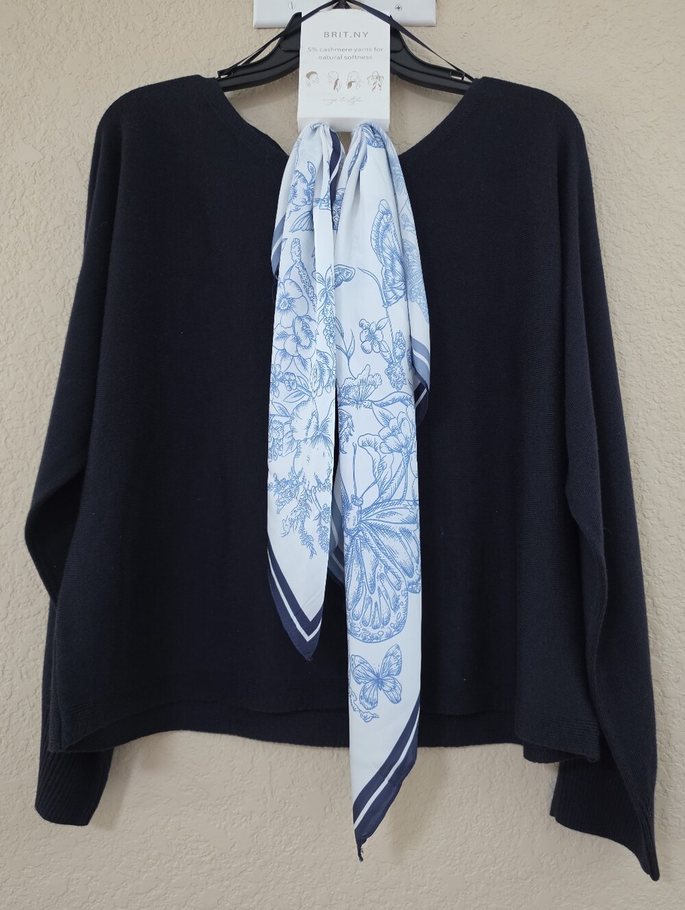 NEW BRIT.NY navy sweater features a draped white and blue butterfly-print scarf.